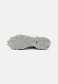 Baskets de course avec une tige légère bleue, surface texturée et une semelle extérieure en caoutchouc blanc dotée de motifs de traction agressifs.
