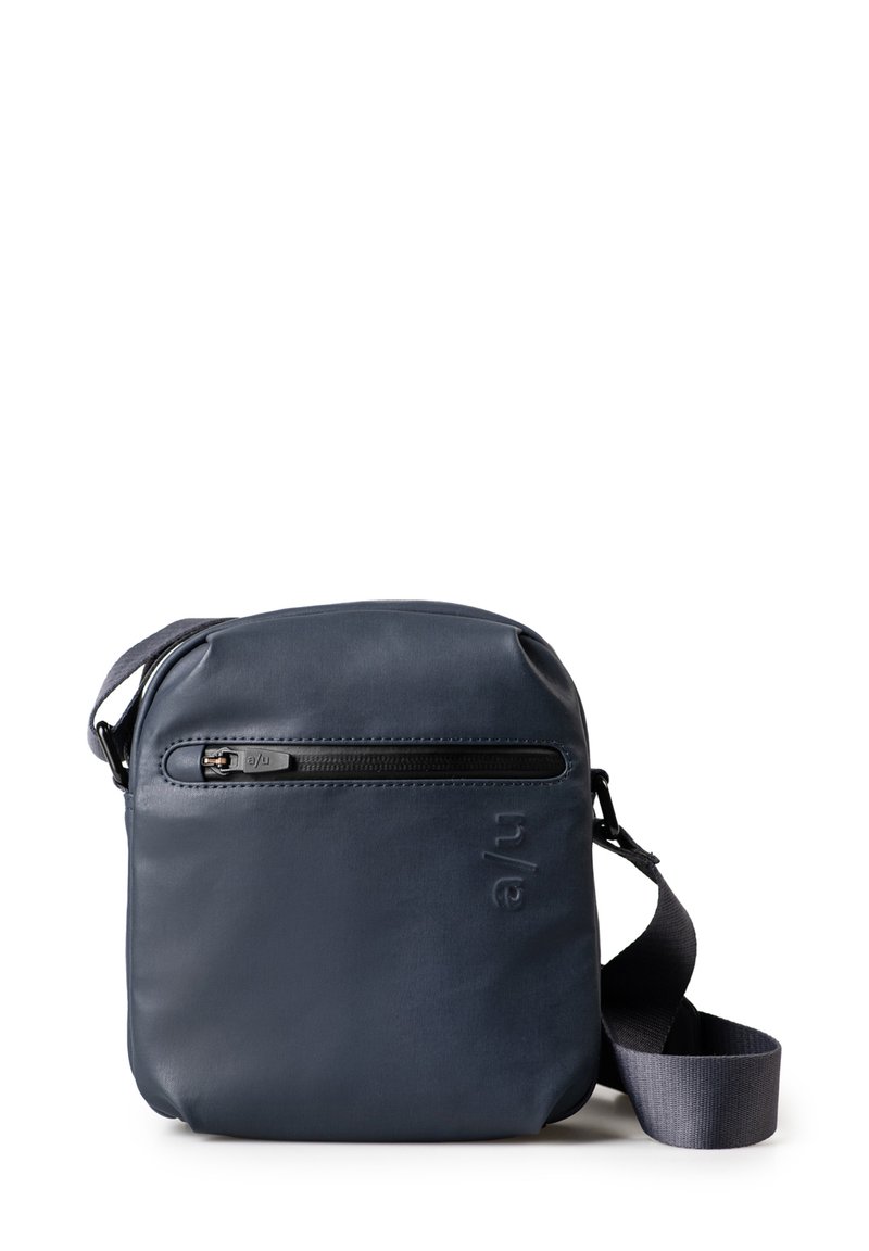 Marineblaue Umhängetasche aus glattem Material mit einem Reißverschluss-Frontfach, verstellbarem Riemen und geprägtem Logodetail an der Seite. Kompaktes Design.