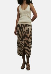 Kerman neule tank top, jossa on istuva bodice ja leveät hihnat, yhdistettynä keskipitkään ruskeaan tiikeri- tai zebrakuosiseksi hameeseen, jossa on sivureikä. Mustat nauhaketjut.