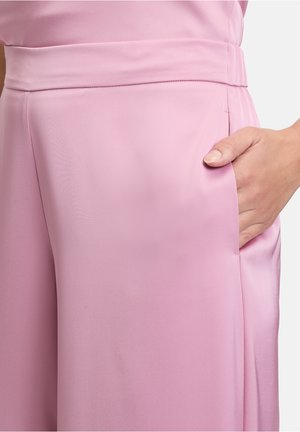 Roze satijnen stof met een wijde broekspijpenontwerp, een platte tailleband en zijzakken. Soepele textuur en subtiele glans zijn zichtbaar.