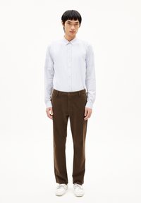 Chemise à manches longues rayée bleue claire, pantalon marron et chaussures blanches ; comporte une fermeture à boutons, une coupe régulière et un design à jambe droite.