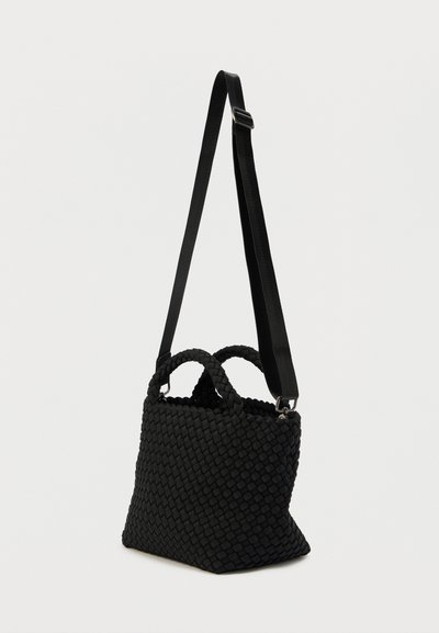 Μαύρη υφαντή τσάντα χειρός με διπλές λαβές και ρυθμιζόμενο λουράκι. Υφή επιφάνειας, τριγωνικό σχήμα και ανοιχτό πάνω μέρος σχεδιασμού.