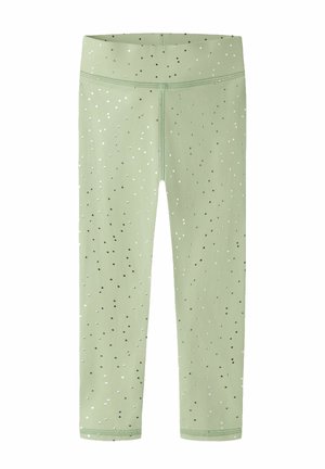 Leggings vert clair avec une taille haute et un petit motif de points noirs et blancs dispersés, présentés à plat sur un fond blanc.