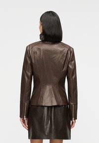 Καφέ δερμάτινο μπουφάν με εφαρμοσ τή γραμμή, υφασμένο μοτίβο σε σχήμα διαμαντιού στην πλάτη, φερμουάρ στα μανίκια και λεία υφή.