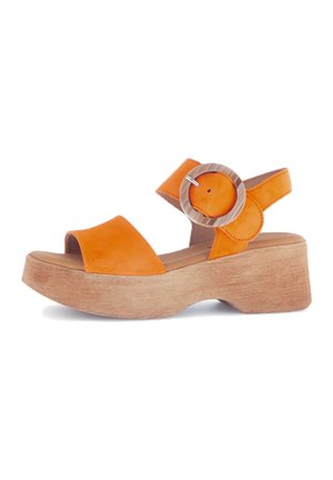 Orange leather sandals with a wooden block heel, featuring two straps and a circular metallic accent on the ankle strap.