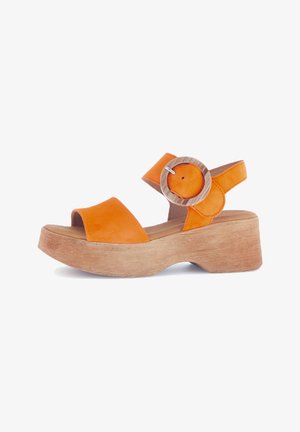 Orange leather sandals with a wooden block heel, featuring two straps and a circular metallic accent on the ankle strap.