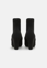 Stivaletti neri con tacco, con tomaia in maglia e dettagli in suede, caratterizzati da una punta tonda e un tacco largo, progettati per una silhouette aderente.