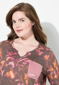 Maglietta marrone con stampa floreale in rosa e arancio. Presenta un collo a V e una tasca sul petto sinistro con la scritta "PURE sleep." Tessuto morbido.
