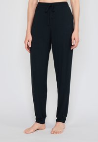 Tmavé, lehké kalhoty na volný čas vyrobené z měkké látky. Obsahují elastický pas se šňůrkou a přiléhavé manžety na kotnících.