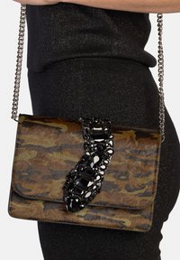 Borsa con motivo mimetico e dettaglio gioiello nero, dotata di una tracolla a catena e texture liscia. Forma rettangolare compatta.