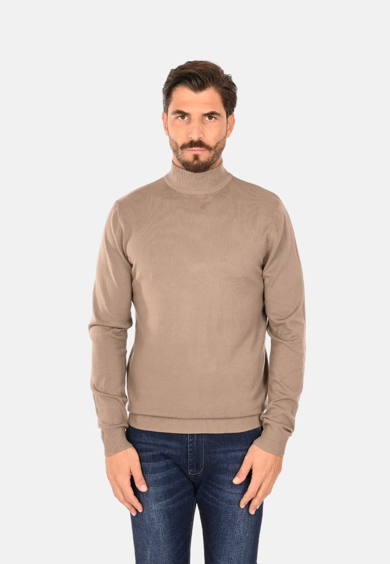 Maglione beige a collo alto realizzato in materiale morbido, con trama a coste su collo e polsini, design aderente, abbinato a jeans blu scuro.
