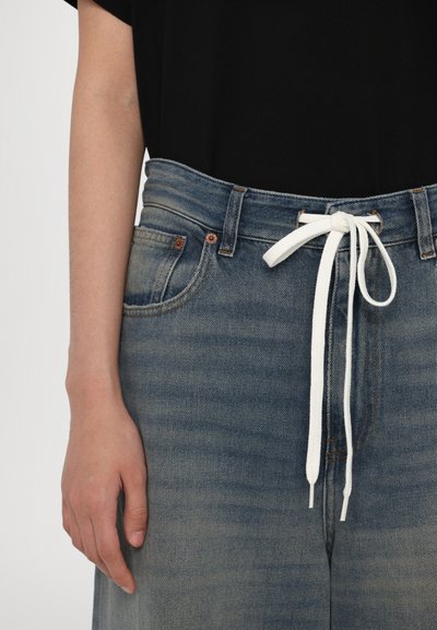 Jeans in denim con gamba affusolata, lavaggio azzurro chiaro, cordoncino bianco e rivetti in rame. Presentano tasche anteriori e una texture morbida.