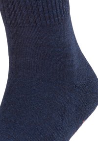 Mørkeblå sokk med glatt tekstur, ribbet mansjett og forsterket hæl. Har en tett passform og subtil fargevariasjon i stoffet.