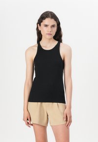 Black sleeveless tank top with a round neckline, fitted design, and smooth texture. Worn with beige shorts, featuring a simple style.