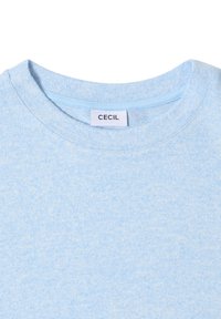Maglietta azzurra chiara con scollo rotondo, realizzata in tessuto morbido. Presenta un'etichetta piccola con il nome del marchio "CECIL" sul colletto.