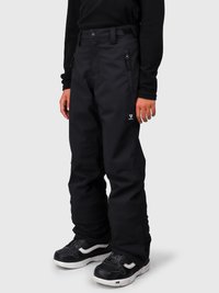 Barn i svarte snøbukser med glidelås lommer på siden og svarte sneakers med hvite såler på en ensfarget bakgrunn.