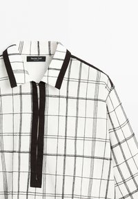 Bílá košile s černým mřížkovým vzorem, černým lemováním na límci, légě a ramenním švu, označená Massimo Dutti.
