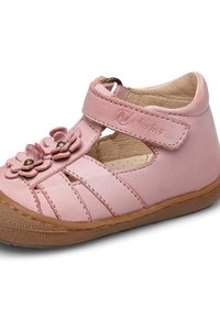 Rosa lädersko med rem och blommig detalj. Har utskärningar och en gummisula. Inuti är den beige med perforerad detalj.