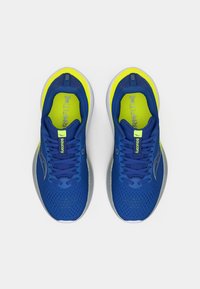 Baskets de course bleu avec une tige en mesh, accents jaunes, col rembourré, semelle grise et texture imprimée pour une adhérence et flexibilité améliorées.