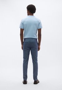 Ανοιχτό μπλε κοντομάνικο πόλο μπλουζάκι με υφή, συνδυασμένο με σκούρο μπλε παντελόνι κανονικής γραμμής. Η ενδυμασία διαθέτει εφαρμοστή σχεδίαση.