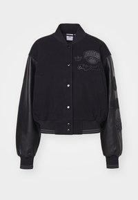 Zwarte varsityjack met een wollen lichaam en leren mouwen, eigenschappen geborduurde logo's en patches, ribgebreide manchetten en zoom, gecropt ontwerp.