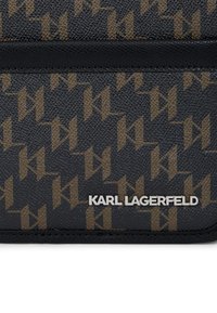 Fekete texturált anyagú pénztárca arany és barna ismétlődő logó mintával, elöl kiemelkedő ezüst "KARL LAGERFELD" logóval.