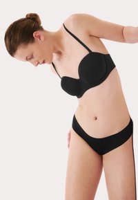 Černá tvarovaná podprsenka s tenkými nastavovacími ramínky a odpovídajícími bikinovými kalhotkami. Hladký povrch, minimalistický design, bezšvové okraje.