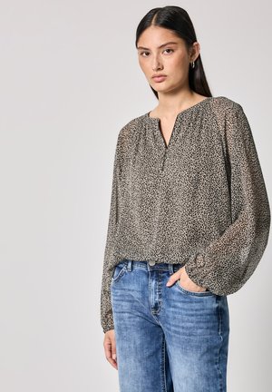 Blouse à imprimé léopard, à manches longues avec un col froncé, en tissu léger ; associée à un jean en denim bleu.