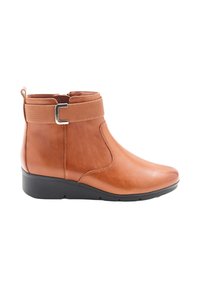 Botte de cheville en cuir brun avec une finition lisse, bande élastique, accent en métal argenté et semelle en wedge noire basse. Présente une fermeture éclair sur le côté.