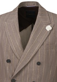Bronzefarbene gestreifte Doppelreiher-Blazer mit Fischgrätenmuster, schwarzen Knöpfen und einer weißen Blumen-Anstecknadel. Das Innere verfügt über ein kontrastierendes Futter.