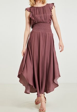 Hihaton omenankukanvärinen mekko, jossa röyhelöiset hartiat, kuminauhavyötärö ja epäsymmetrinen liehuva helma, yhdistetty beigen väristen remmikenkien kanssa.