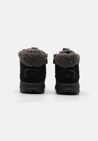 Crne suède čizme do gležnjeva sivi krzneni obod i stražnji patentni zatvarač. Imaju trakicu za lakše obuvanje i teksturirani gumeni đon za prianjanje.