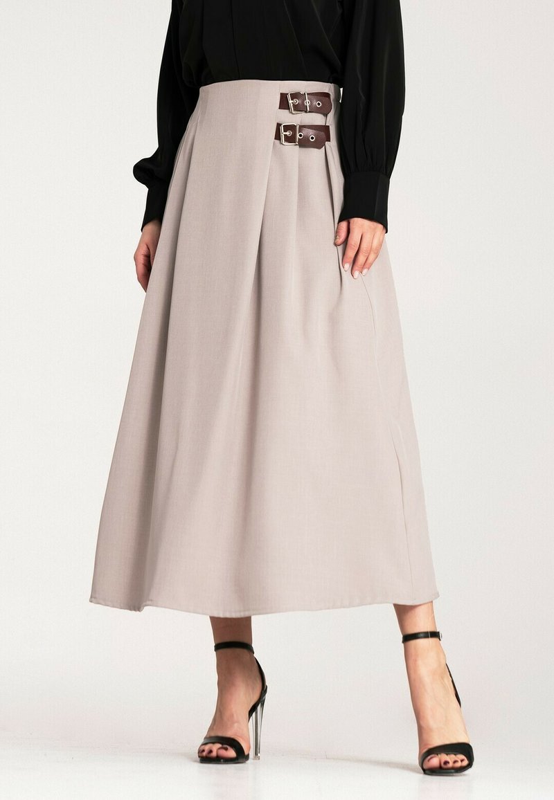 Beżowa plisowana spódnica z wysokim paskiem, wyposażona w dwa brązowe skórzane paski z srebrnymi klamrami, wykonana z gładkiej tkaniny, sięgająca do podłogi.