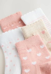 Vijf baby sokjes in pasteltinten met hart- en stippenpatronen in roze, wit en beige, overlappend gerangschikt op een witte achtergrond.