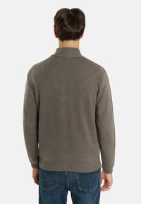 Maglione grigio lavorato a maglia con colletto alto, polsini e orlo a coste. Presenta un motivo testurizzato, mostrato da dietro.