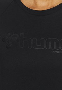 Camisa negra de manga corta hecha de una tela suave con un sutil diseño de logo en relieve. Cuello redondo y corte ajustado.