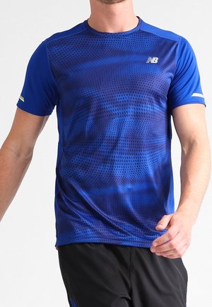 Homme portant un t-shirt de sport à manches courtes bleu New Balance avec un motif à points et un short noir, marchant en avant.