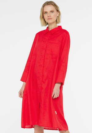 Red button-up dress made of textured fabric, featuring a collar, long sleeves, and a side pocket for added detail.
