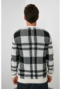 Suéter a rayas en blanco y negro con mangas largas, puños y dobladillo acanalados, textura de punto, que presenta un gran patrón de cuadros en la parte posterior.