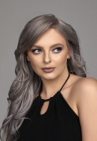 Model met lang, golvend zilver haar, die een zwart mouwloos topje met een sleutelgat-halslijn draagt. Huidtint is licht, en de gelaatskenmerken zijn goed gedefinieerd.
