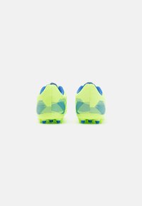 Botas de fútbol amarillas brillantes con acentos azules, parte superior texturizada, rayas horizontales distintivas y tacos moldeados para tracción en hierba.