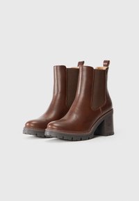 Brune lær ankle boots med elastiske sidepaneler, en struktureret høj hæl og en gummisål. Har en pull-loop bagpå for nem påtagning.
