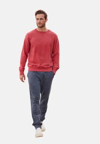 Rode katoenen sweatshirt met ronde hals, geribbelde manchetten en zijkanten, gecombineerd met blauwe joggingbroek en witte sneakers. Casual, ontspannen pasvorm.