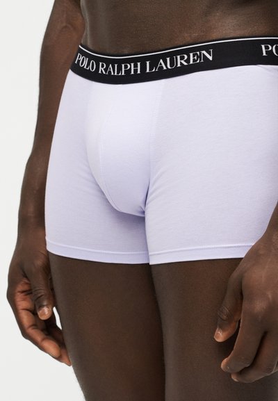 Κοντινό πλάνο ενός ατόμου που φοράει λευκά boxer Polo Ralph Lauren με μαύρη μέση που φέρει το όνομα της μάρκας με λευκό κείμενο.