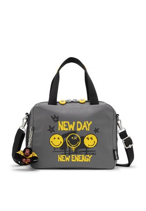 Bolso rectangular gris con asas y correa negras, caras sonrientes amarillas, texto "NEW DAY NEW ENERGY" y un pequeño llavero negro de mono adjunto.