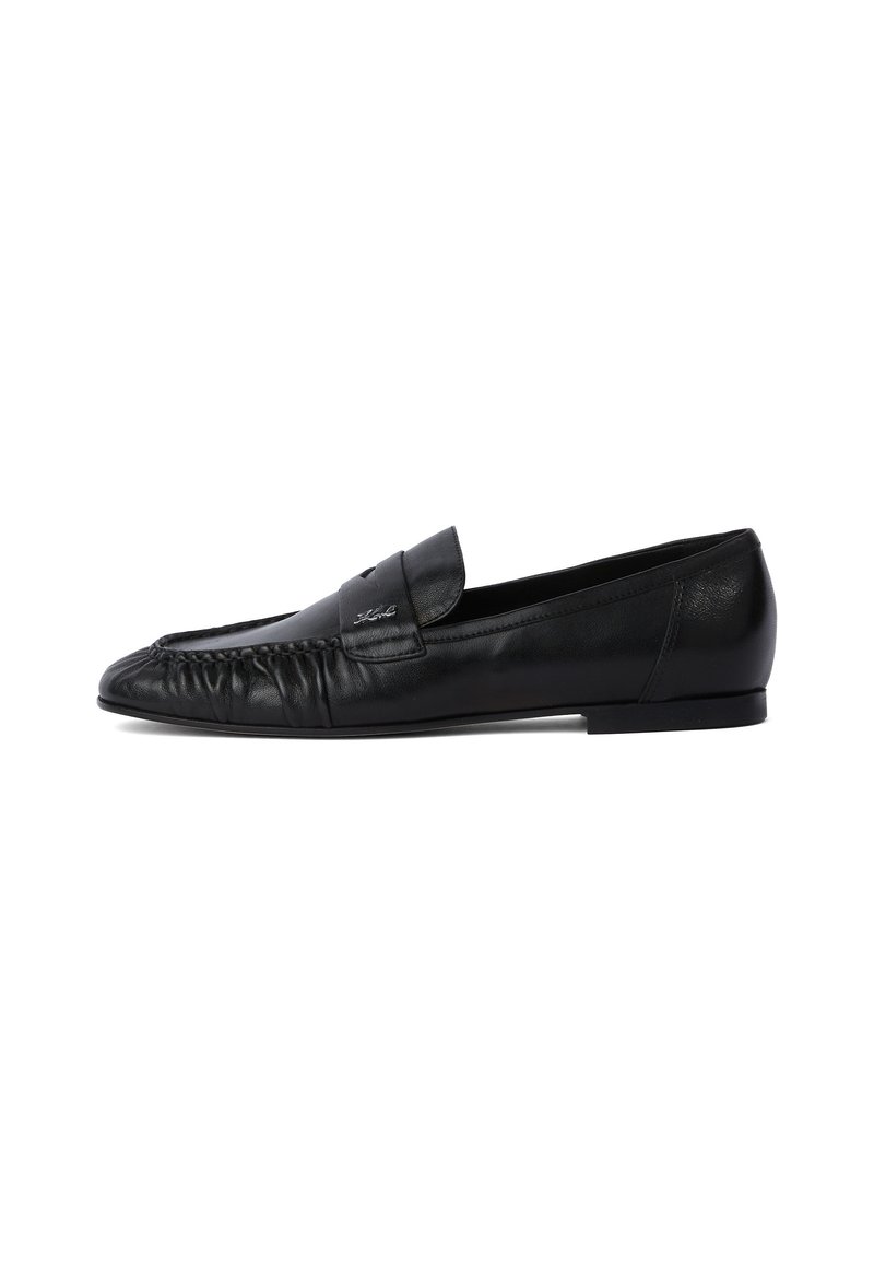 Mocasin din piele neagră cu vârf rotunjit, detalii cusute în față și talpă plată. Design minimalist cu un accent discret al logo-ului.