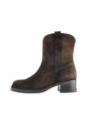 Stivale alla caviglia in suede marrone con punta arrotondata, pannelli elastici laterali e tacco basso a blocco. Caratterizzato da una texture liscia e un design minimalista.