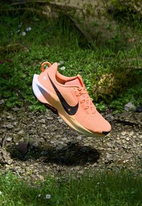 Nike hardloopschoen in fel oranje met zwarte accenten, met een ademend bovenwerk van mesh, een getextureerde zool en een vetersluiting.