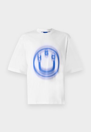 T-shirt en coton blanc avec un design graphique bleu représentant les lettres "HUGO" et une forme circulaire, avec un effet légèrement flou.