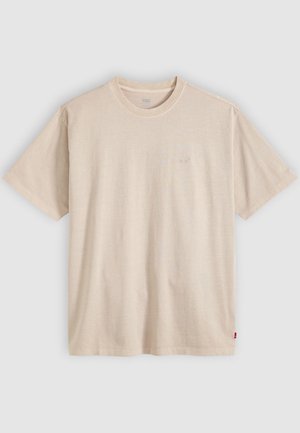 T-shirt beige à manches courtes avec col rond, logo Levi’s discret sur la poitrine et petite étiquette rouge sur la couture latérale.